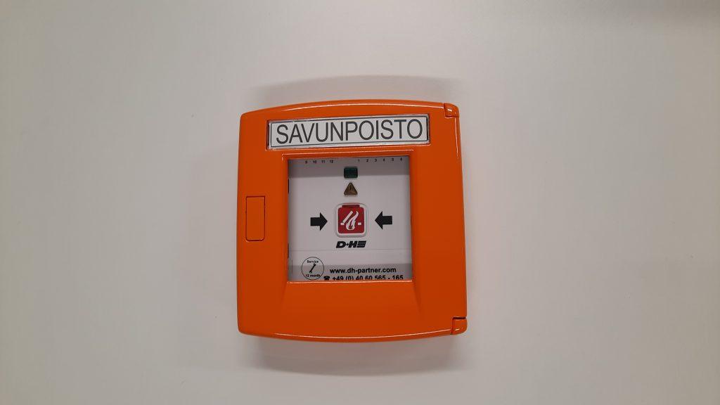 RT45 Savunpoistoluukun painike. Lasin rikkomalla pääset painamaan savunpoistonappia.